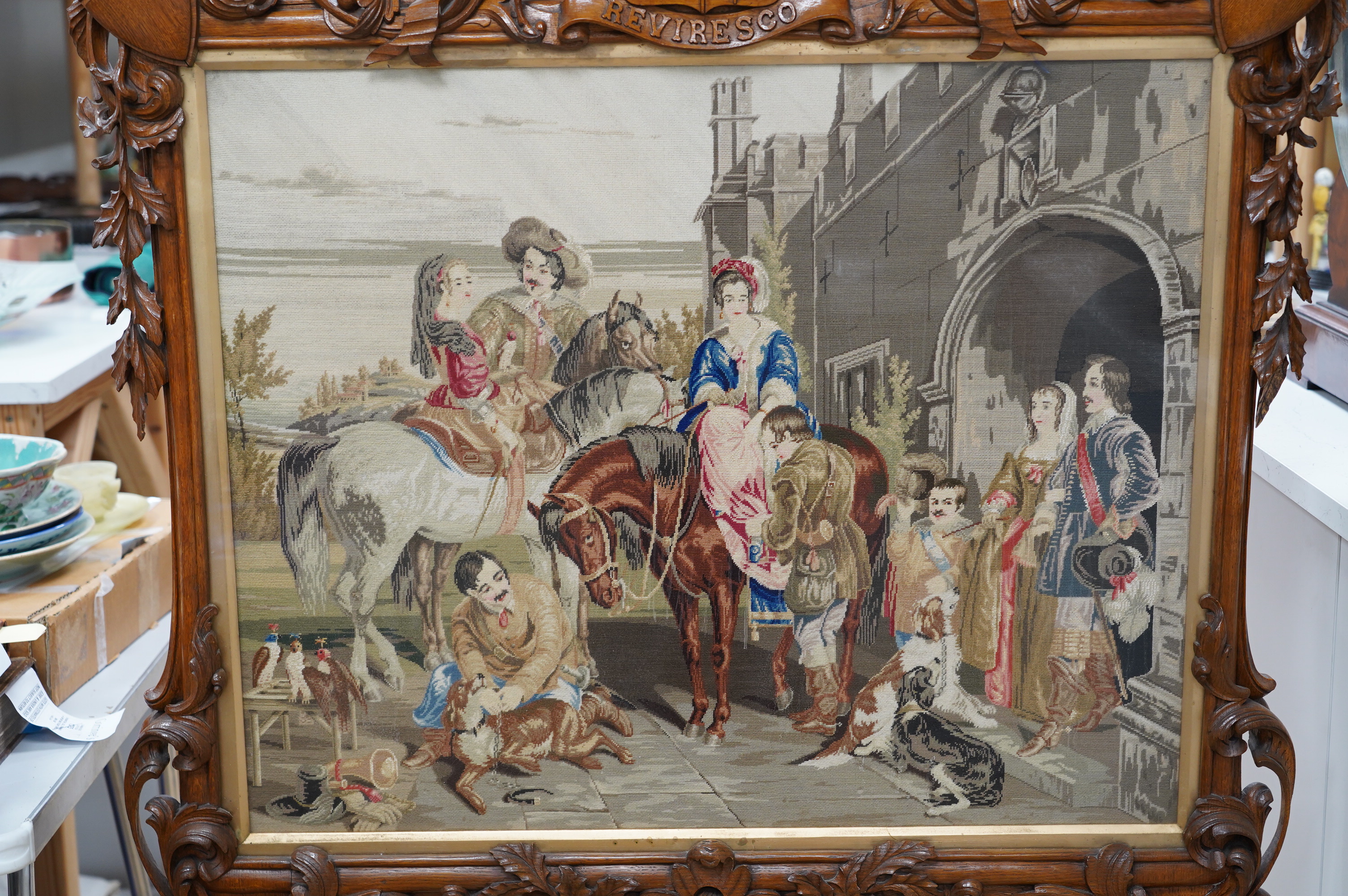 A large 19th century ornately carved oak fire screen, carved with hoof feet and a finely worked petite point panel of a Jacobean family preparing for a falconry hunt. 148cm high, 87cm wide, petite point panel 69cm wide,